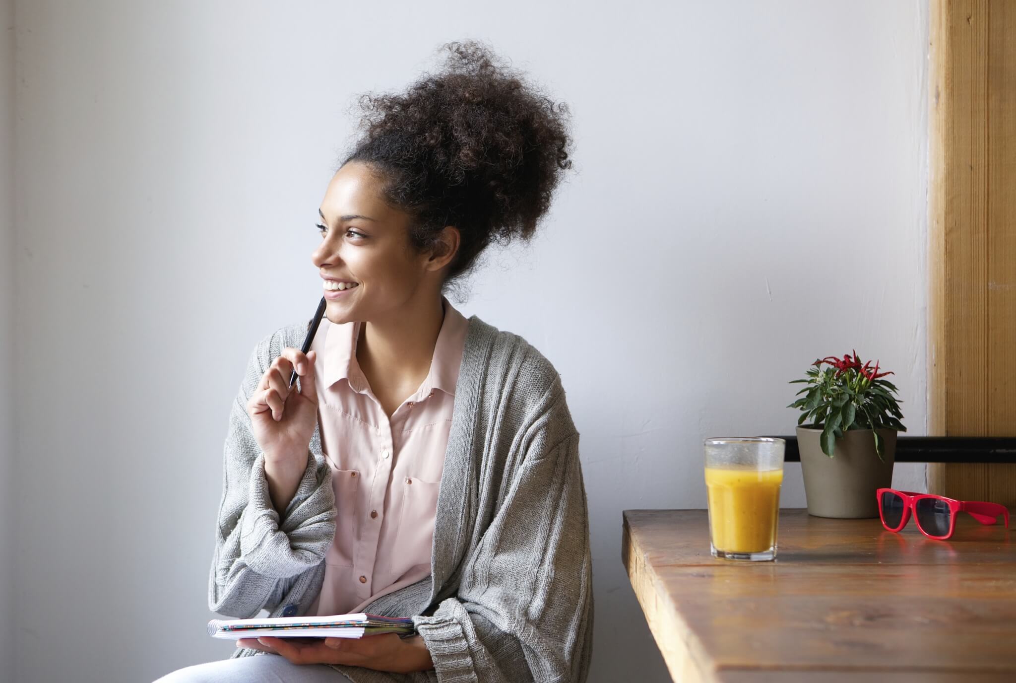 Happy young woman sitting at home with pen and paper 000067132741 Large