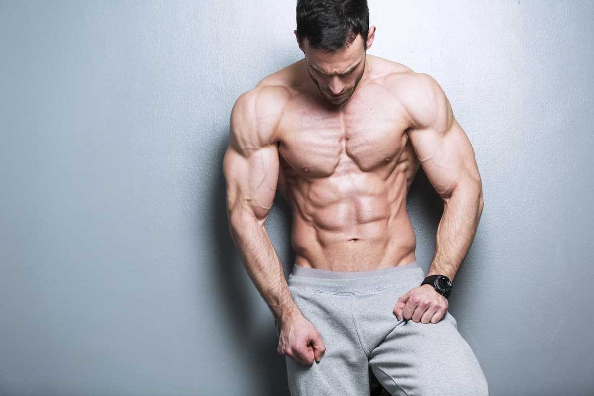 Topless muscular man leaning on a gray wall 000061246532 Large jpg