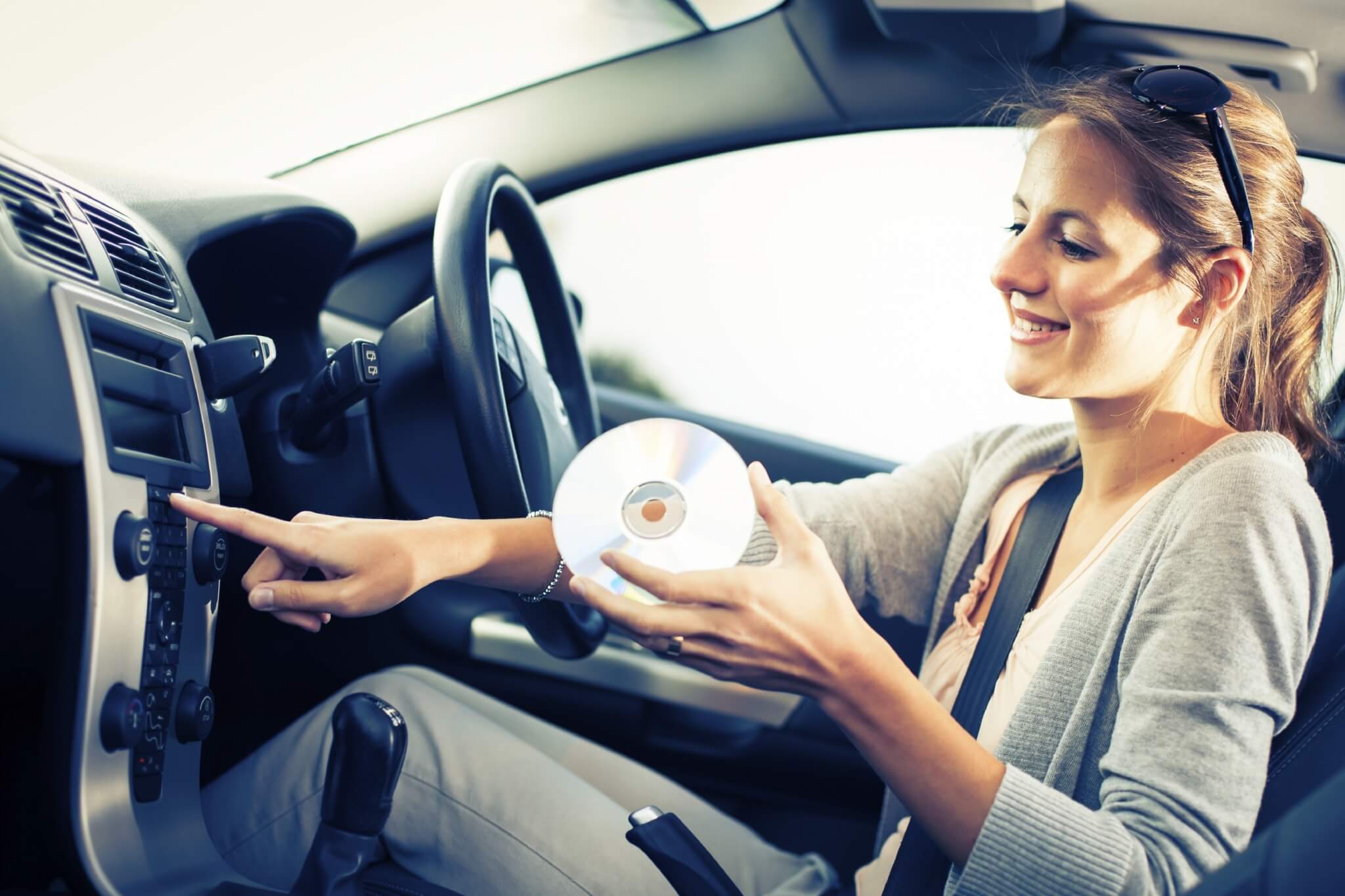 Young female driver playing music in the car 000070272949 Large jpg