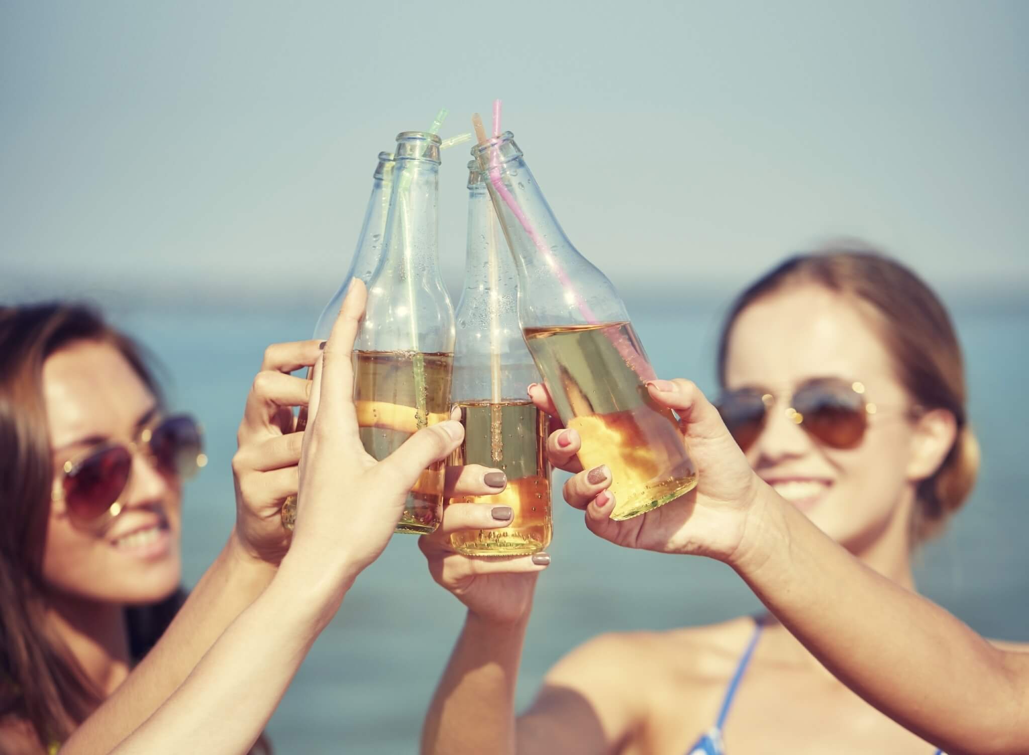 Close up of happy young women with drinks on beach 000069864029 Large 2 jpg